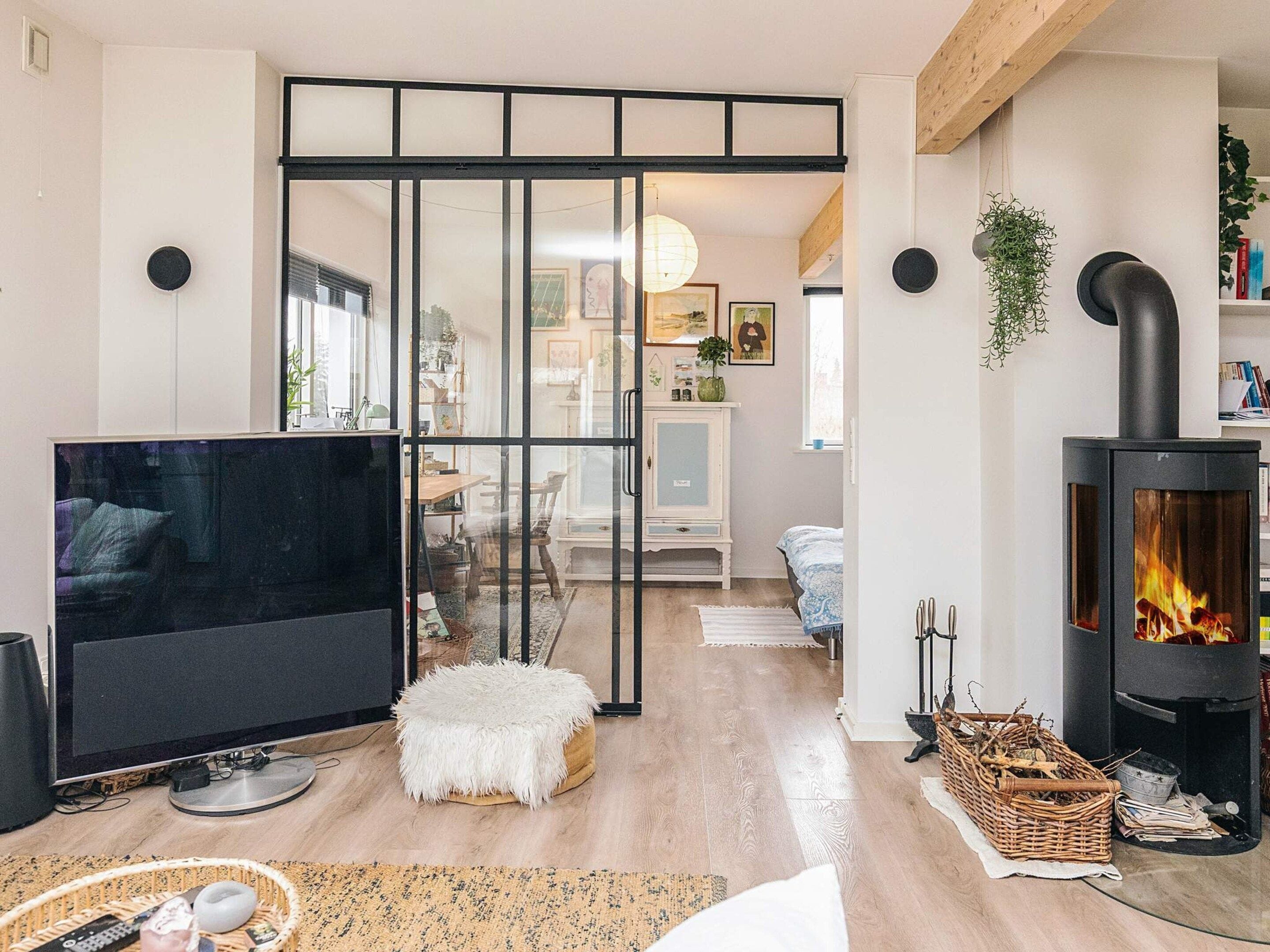 A living room with a TV, a fireplace, a sliding glass door, and a wooden floor.