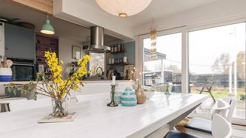 Een moderne keuken met een groot schiereiland, een hanglamp en uitzicht op het buiten.