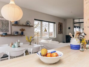 A modern kitchen with a bowl of fruit on the counter, a hanging light fixture, and a window with a view. - 6 Person Holiday Home in Rude (Bisserup)