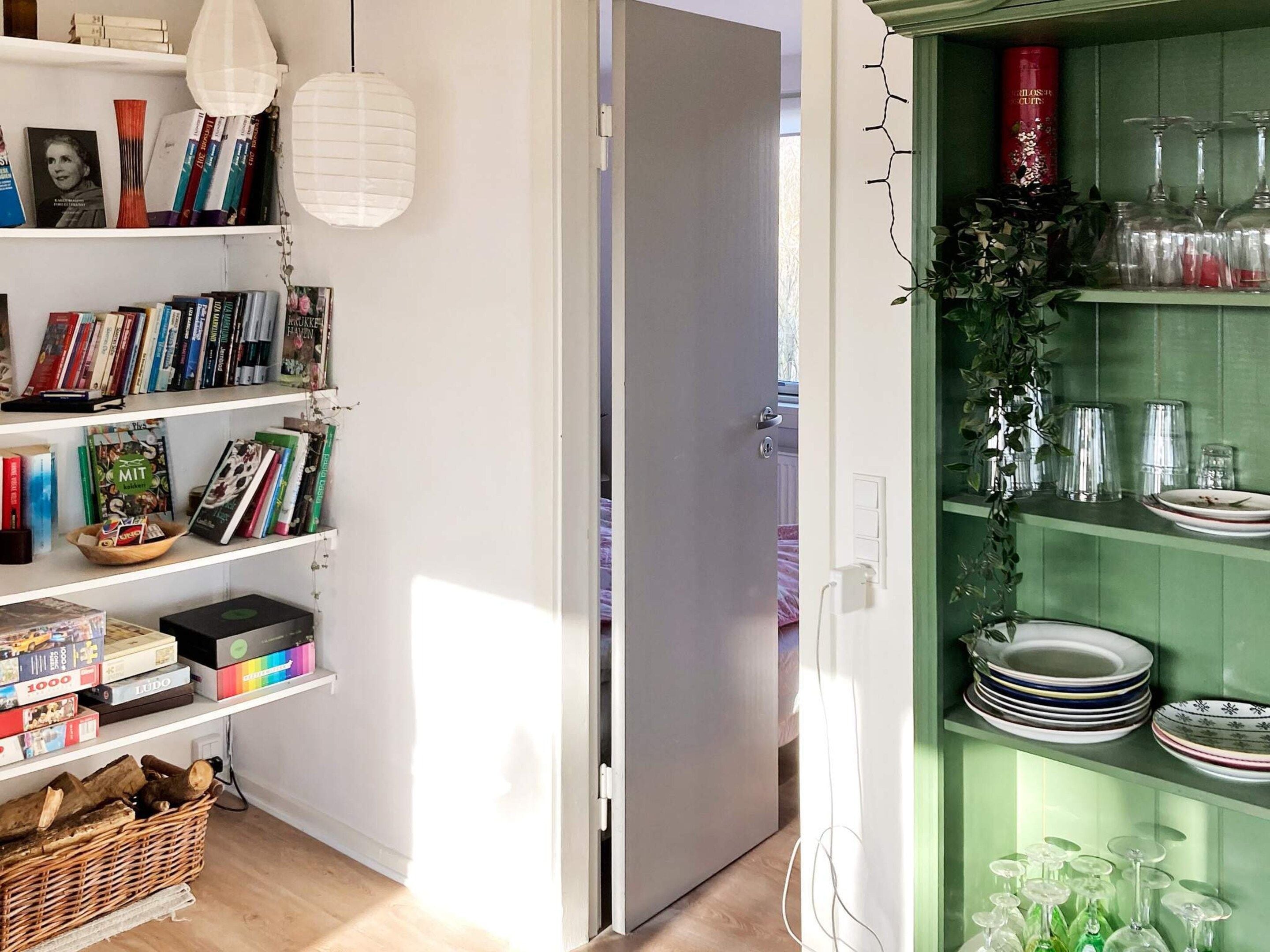 Ein Zimmer mit Bücherregal, einem Essbereich mit Tellern und Gläsern und einer Tür zu einem weiteren Raum.