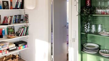 Ein Zimmer mit Bücherregal, einem Essbereich mit Tellern und Gläsern und einer Tür zu einem weiteren Raum.