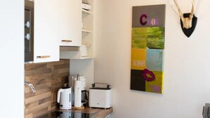 Une cuisine moderne avec des armoires blanches, un pare-feu en bois, une machine à café, un grille-pain et une décoration murale représentant des bois de cerf.