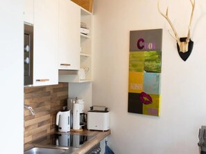 Une cuisine moderne avec des armoires blanches, un pare-feu en bois, une machine à café, un grille-pain et une décoration murale représentant des bois de cerf.