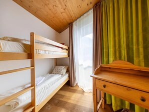 Habitación con literas, un escritorio de madera y una ventana con cortinas.
