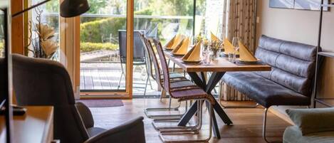 Un espace repas moderne avec une table en verre, des sièges en cuir et une vue dégagée grâce à de grandes fenêtres.