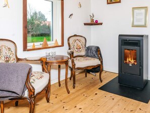 Una sala de estar acogedora con piso de madera, chimenea y dos sillones tapizados con motivos florales.