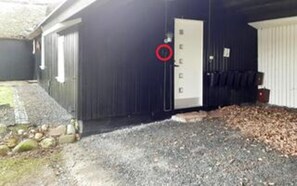 A building with a garage door, a door, and a small outdoor area with gravel and some rocks.