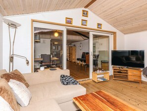 Una sala de estar con sofá, mesa de centro, televisor y puerta corrediza de vidrio que da a un comedor.