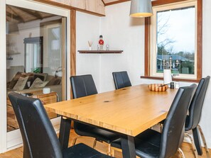 A dining area with a wooden table, black chairs, and a hanging light fixture. - 8 Person Holiday Home in Farso (Farso)