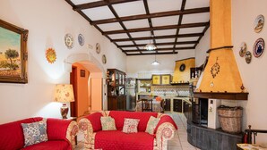 Una sala de estar acogedora con un sofá rojo, una mesita de centro y una zona de cocina con estufa y armarios.