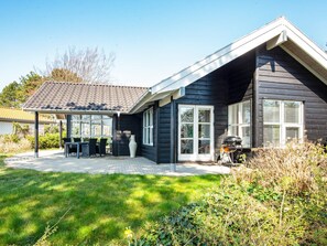 A modern house with a covered patio, a barbecue area, and a well-maintained lawn.