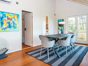 Un espace repas moderne avec une table en bois, des chaises grises et un tapis rayé noir et gris.