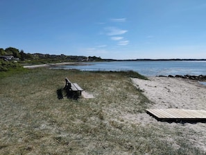 Ein Strand mit einer Holzbank und einem Holzsteg.