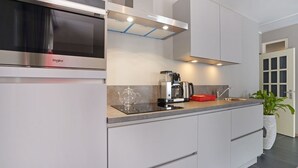 Cozinha moderna com micro-ondas embutido, máquina de café e uma cesta vermelha.