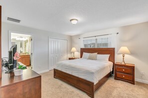 A bedroom with a wooden bed, two bedside tables with lamps, a dresser, a TV, and a window with blinds. - "Pequod Lakeview" - 4BD/3BA Townhome near Disney (Kissimmee)