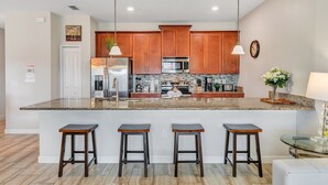 A modern kitchen with wooden cabinets, stainless steel appliances, and a granite countertop. - "Pequod Lakeview" - 4BD/3BA Townhome near Disney (Kissimmee)