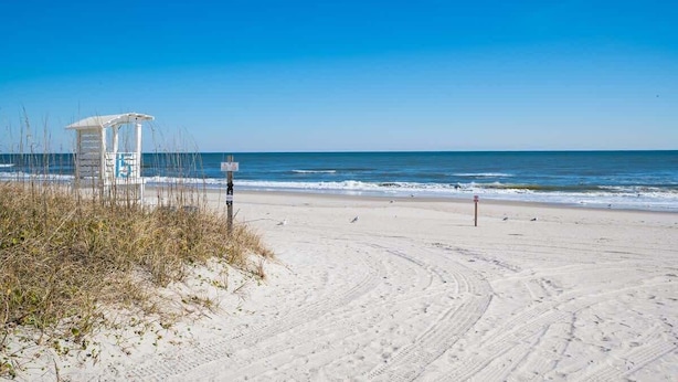 A beach with a lifeguard tower, sandy beach, and ocean.