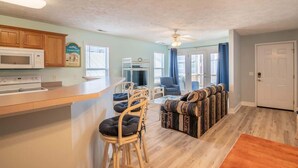 A spacious kitchen with a microwave, wooden cabinets, and a dining area with chairs and a patterned sofa.