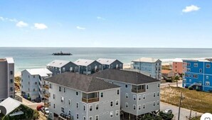 A coastal residential area with multi-story buildings, a beach, and a ferry in the distance.