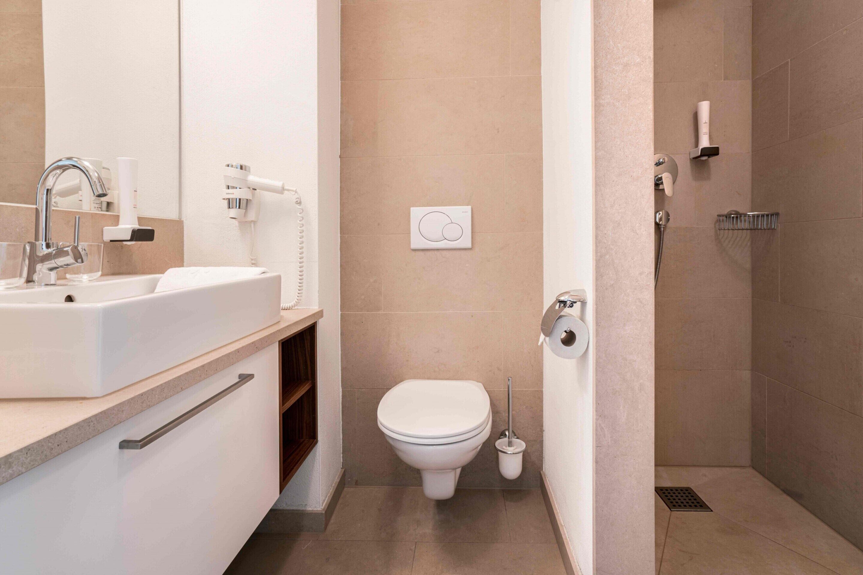 A modern bathroom with a sink, toilet, and shower.