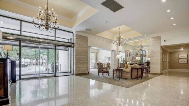A spacious lobby with a polished floor, a grand chandelier, and a seating area with a table and chairs. - Modern Twist in Historic Building, sleeps 6 (Atlanta)