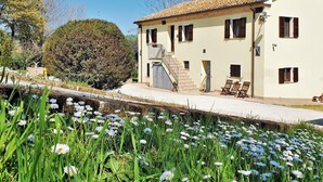 A two-story building with a tiled roof, a staircase leading to the upper floor, and a small garden area with flowers and shrubs. - Holiday House in Filottrano on the Beach by the sea (Filottrano)