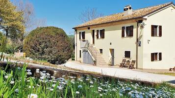Traditional Mediterranean-style building with a tiled roof and balcony seating area overlooking a beautifully maintained garden.
