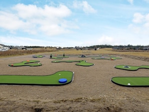 Um campo de prática de golfe com vários tapetes de treino e bolas de golfe.
