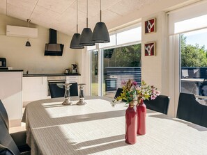 Cozinha moderna com área de jantar, janelas amplas e vista para o exterior.