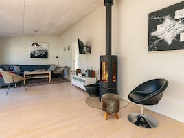 Una sala de estar moderna con una estufa de leña, un sofá, una mesa de centro y una silla.