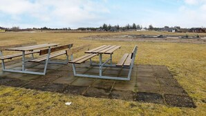 An outdoor area with picnic tables and a paved walkway. - Holiday Home in Brovst (Brovst)