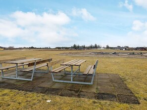 An outdoor area with picnic tables and a paved walkway. - Holiday Home in Brovst (Brovst)