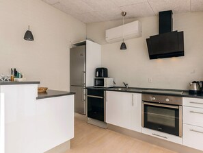 A modern kitchen with a built-in oven, microwave, and stainless steel appliances. - Holiday Home in Brovst (Brovst)