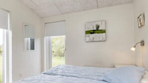 Une chambre à coucher avec un lit, une fenêtre, une porte et une œuvre d’art accrochée au mur.