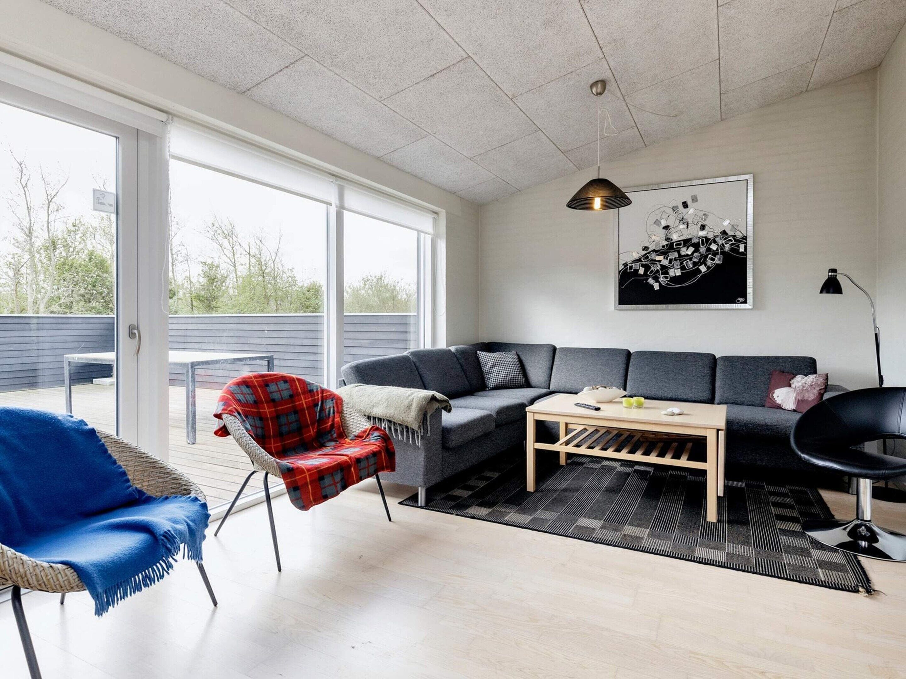 A modern living room with a grey sofa, a red plaid chair, a wooden coffee table, and a black floor lamp.