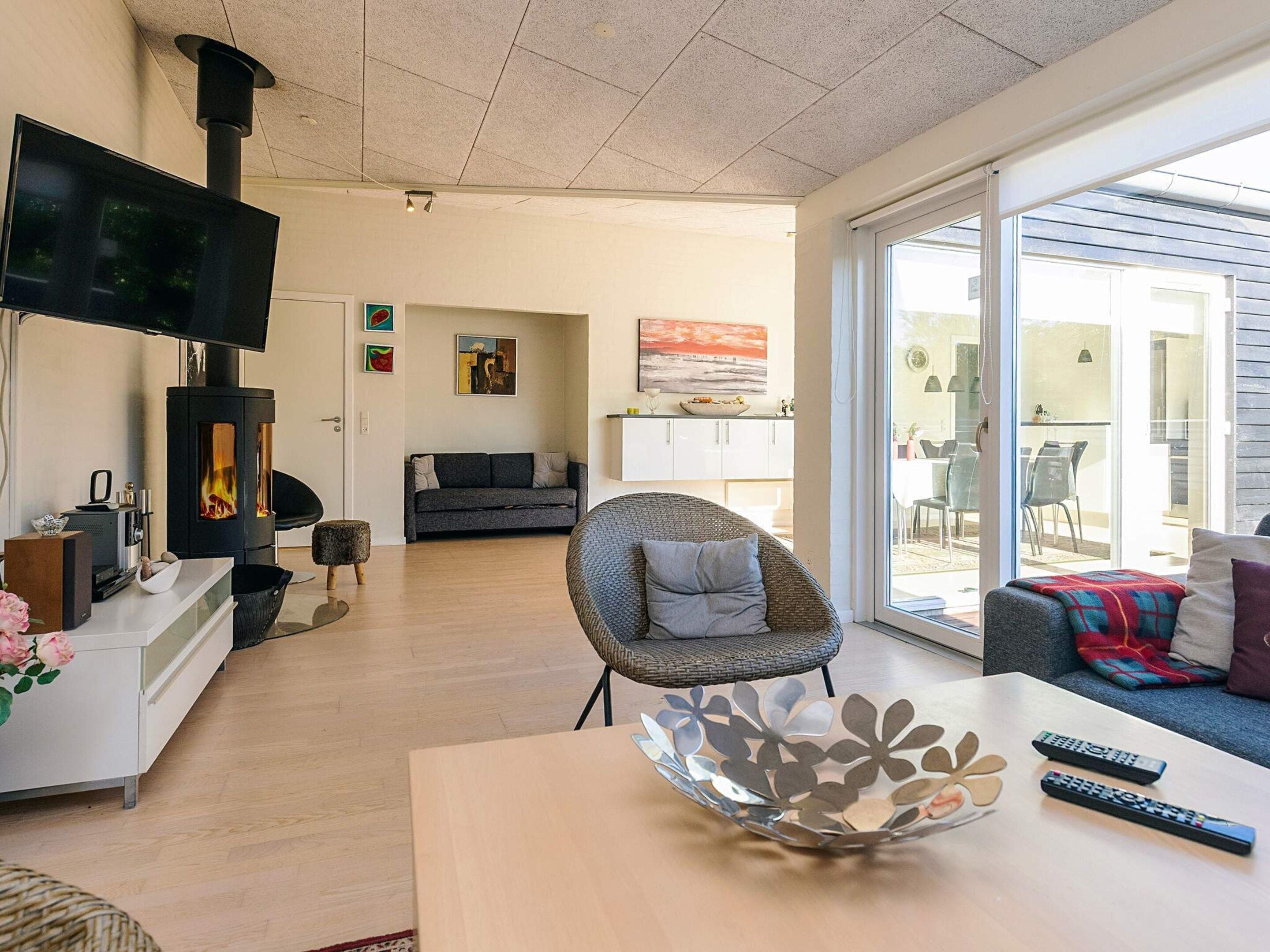 Un salon moderne avec une cheminée, un canapé, un téléviseur et un coin repas offrant une vue agréable.