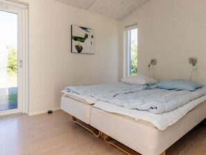 Quarto com cama, janela, porta e uma obra de arte na parede.
