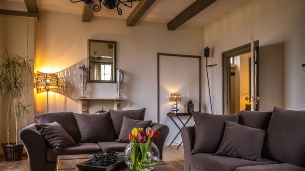 A living room with two sofas, a coffee table with a vase of flowers, and a lamp. - Superb Holiday Home on a Mini Campsite Near the Beach (Vrouwenpolder)