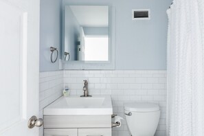 A bathroom with a white sink, mirror, and toilet.