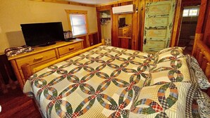 A bedroom with a bed, a dresser, a television, and a window with blinds. - Sunset View over the Mountains! Rustic Cabin w/ Hot Tub (Almond)