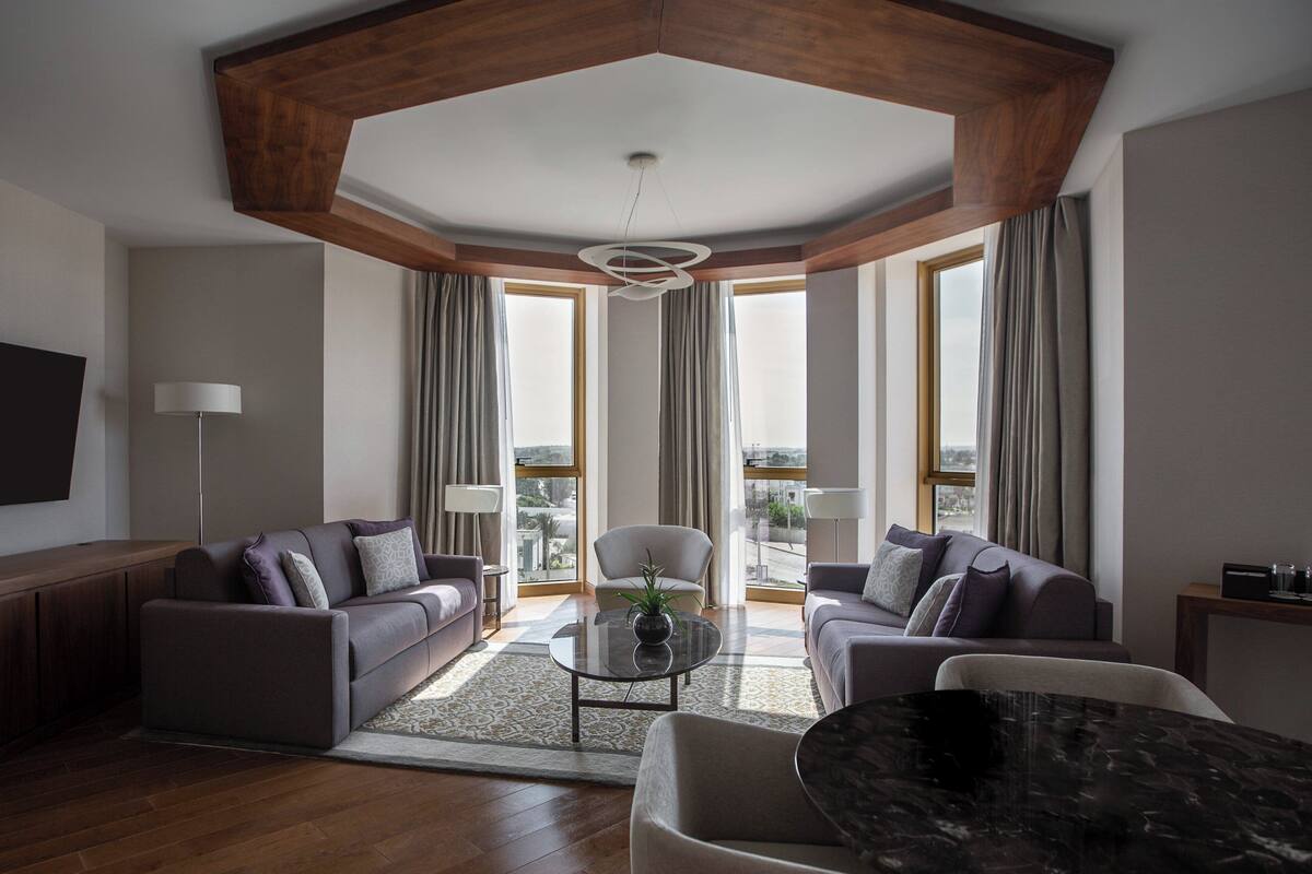 Una sala de estar moderna con techo de madera, dos sofás, una mesa de centro y un televisor.