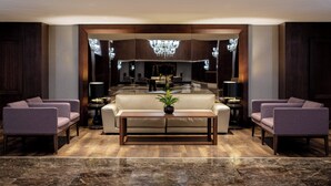 Un lobby moderno con un sofá, sillones, una mesa de centro y una araña.