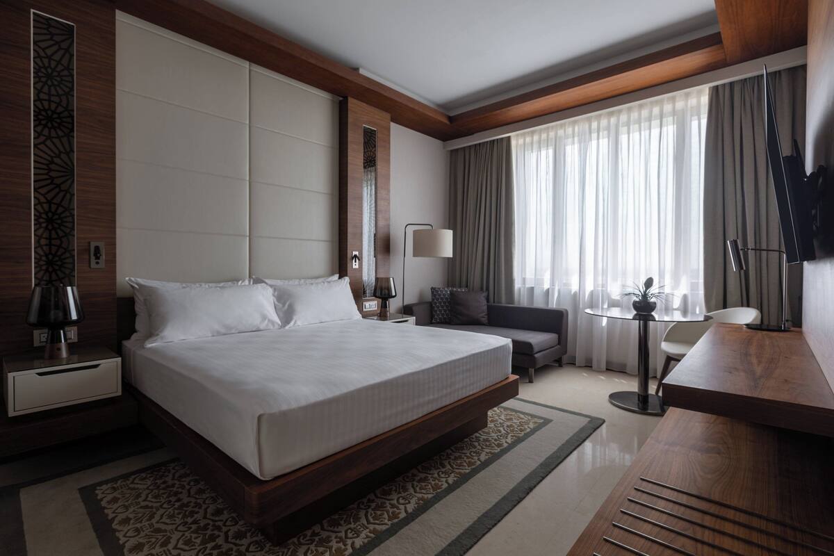 Una habitación de hotel moderna con una cama grande, un escritorio, un sofá y un televisor.