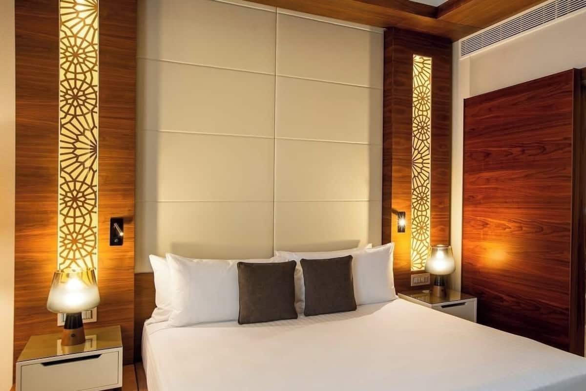 Una habitación de hotel con una cama grande, dos mesitas de noche y paneles decorativos en la pared.
