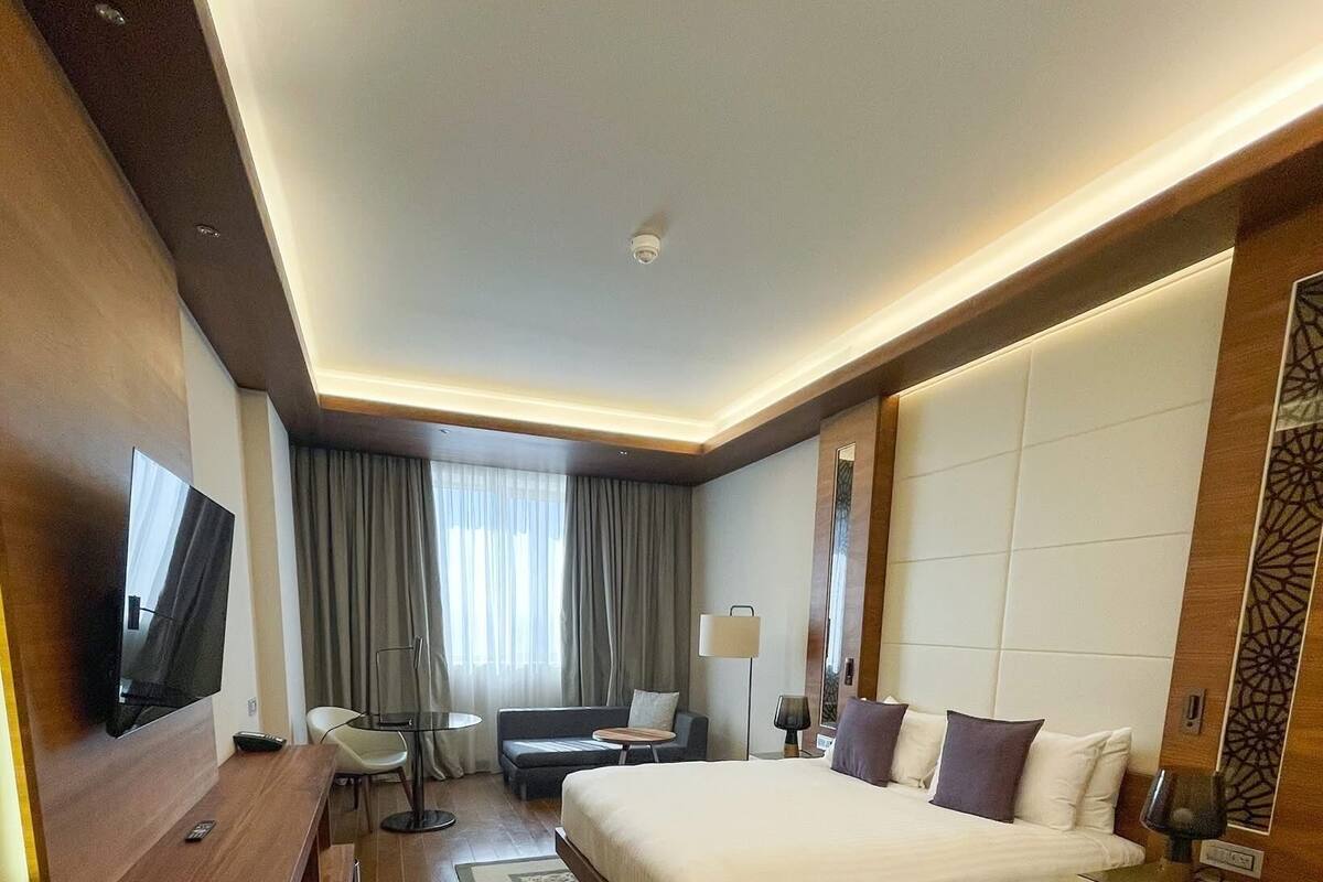 Una habitación de hotel con una cama grande, un escritorio, un televisor y un sofá.