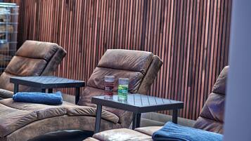Relax in a serene outdoor seating area with two reclining chairs and a small table, perfect for enjoying a refreshing drink.