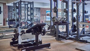 Un gimnasio con diferentes equipos de ejercicio, incluyendo máquinas de pesas y kettelbells.