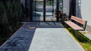 Entrada de hotel con puerta de vidrio, un banco y un camino que lleva al edificio.