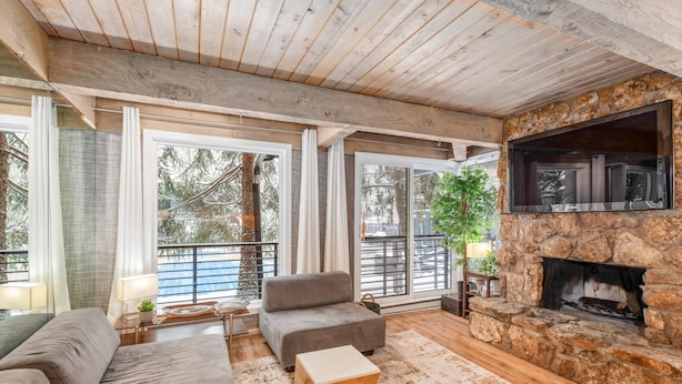 A cozy living room with a stone fireplace, large windows, and a comfortable seating area. - Quiet & Convenient With Great Amenities. Close To Downtown. Large Pool, HT, Fitness Rm. Parking (Aspen)