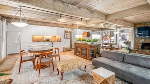 A spacious living area with a wooden ceiling, a round dining table, a gray sofa, and a stone fireplace. - Quiet & Convenient With Great Amenities. Close To Downtown. Large Pool, HT, Fitness Rm. Parking (Aspen)